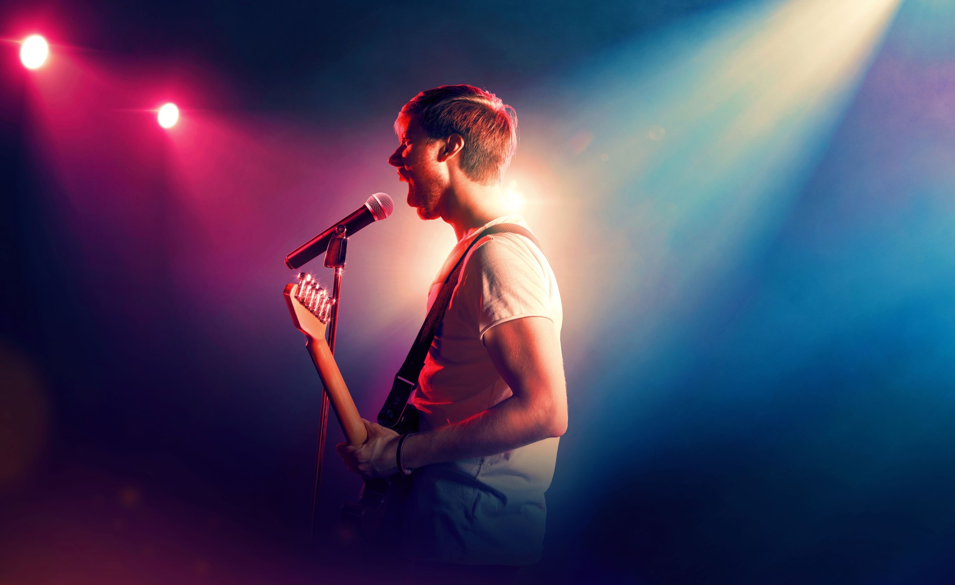 Singer with microphone and guitar performing on stage