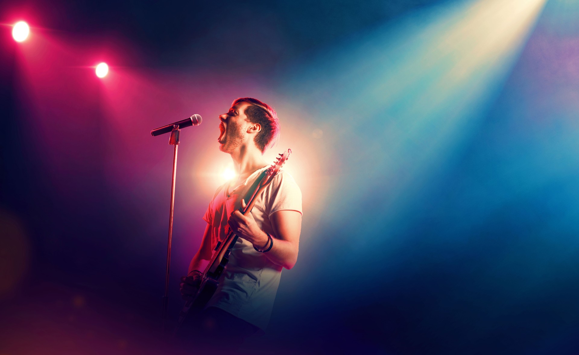 Singer with microphone and guitar performing on stage